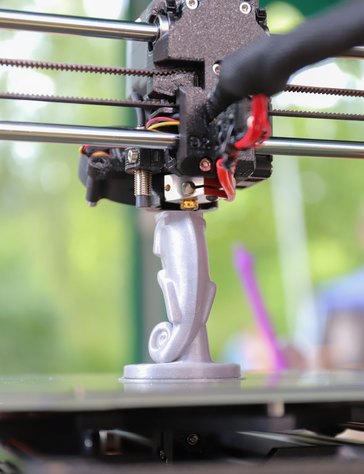 3D printer finishing a silver figurine