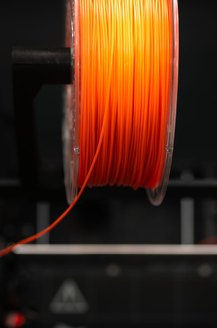 Orange filament feeding into a printer