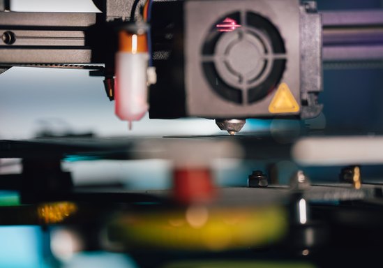 Close-up of a 3D printer nozzle over the build plate